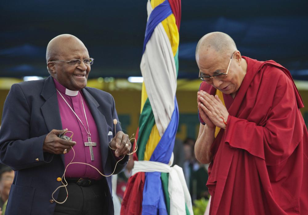 FILE - Anglican Archbishop Emeritus Desmond Tutu, left, holds a microphone as Tibetan spiritual leader the Dalai Lama gestures, as they interact with children at the Tibetan Children's Village School in Dharmsala, India, Thursday, April 23, 2015. Tutu, South Africa’s Nobel Peace Prize-winning activist for racial justice and LGBT rights and retired Anglican Archbishop of Cape Town, has died, South African President Cyril Ramaphosa announced Sunday Dec. 26, 2021. He was 90. (AP Photo/Ashwini Bhatia, File)