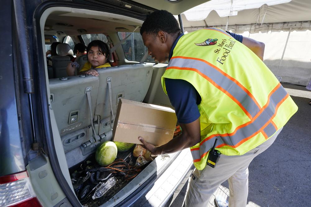 A volunteer fills up a vehicle with food boxes at the St. Mary's Food Bank Wednesday, June 29, 2022, in Phoenix. The food banks are struggling to meet the growing need even as federal programs provide less food to distribute, grocery store donations wane and cash gifts don’t go nearly as far. (AP Photo/Ross D. Franklin)