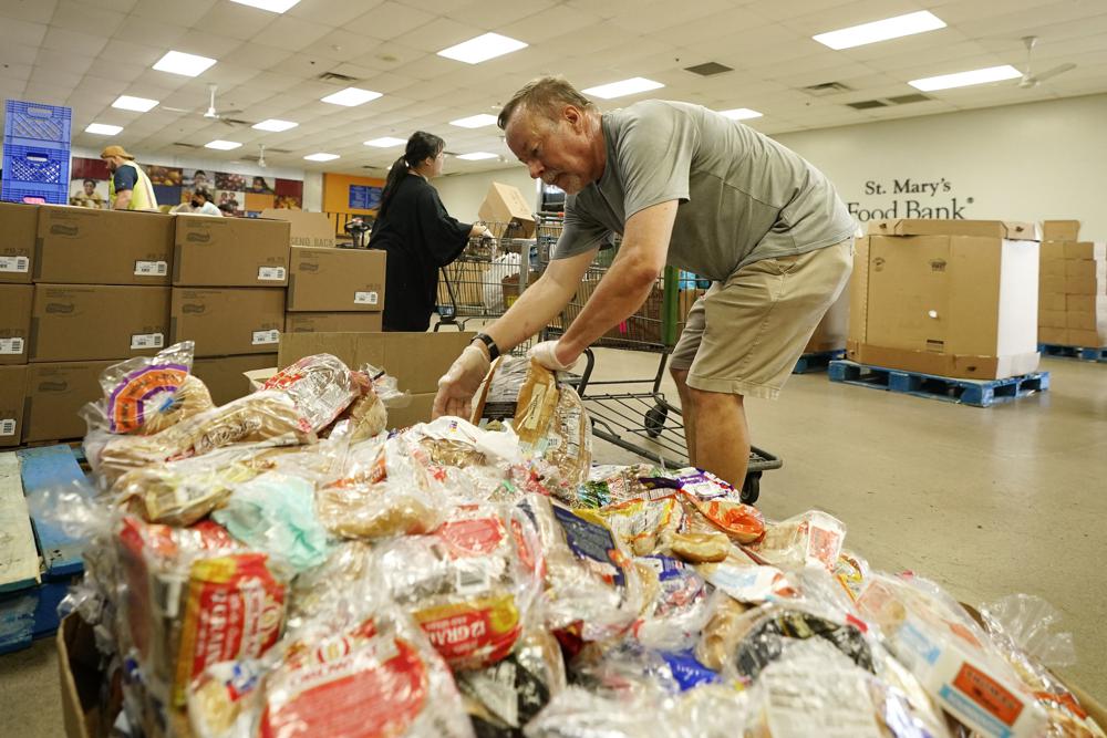 Volunteers fill up grocery carts with food for distribution into drive through vehicles at the St. Mary's Food Bank Wednesday, June 29, 2022, in Phoenix.Long lines are back at food banks around the U.S. as working Americans overwhelmed by inflation turn to handouts to help feed their families. (AP Photo/Ross D. Franklin)