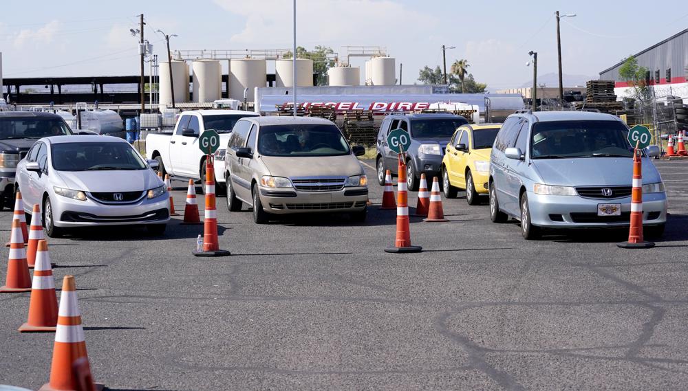 Dozens of vehicles line up to get food boxes at the St. Mary's Food Bank Wednesday, June 29, 2022, in Phoenix. Long lines are back at outside food banks around the U.S. as working Americans overwhelmed by inflation increasingly seek handouts to feed their families. Many people are coming for the first time amid the skyrocketing grocery and gas prices. (AP Photo/Ross D. Franklin)